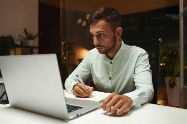 Geliştirici dizüstü bilgisayarda makale okuyor ve notlar alıyor