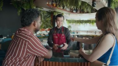 Barın yanında otururken garsona kartla ödeme yapan farklı çiftlerin arka plan görüntüsü