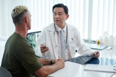 Asyalı doktor askerle tonogramın sonuçlarını tartışıyor.