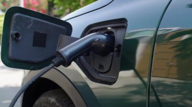 Dışarıdaki elektrikli arabanın şarj portuna takılı siyah kablodan çekilen el kamerası yok.