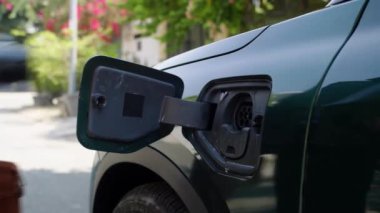 Erkek girişimcinin elektrikli otomobilin şarj portuna kablo yerleştirip ayrılırken elde çekilen fotoğrafı.