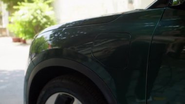 Sokakta elektrikli otomobil limanında şarj kablosu takan tanınmayan kadın sürücünün elleri kesilmiş.