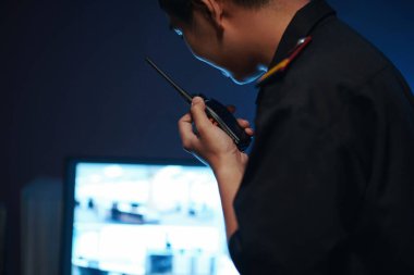 Güvenlik odasında çalışan genç adam telsizle konuşuyor.