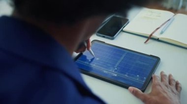 Erkek mimarın omzunun üzerinden. Ofis masasındaki tablet bilgisayarın ekranında binanın çalışma düzeni.
