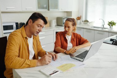 Adam faturaları hesaplarken karısı dizüstü bilgisayar kullanıyordu. Mutfakta oturup ödemeyi tartışıyorlardı.