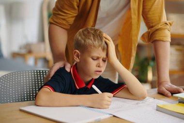 Öğrenci çocuk masada oturuyor ve babasıyla ödev yapıyor.