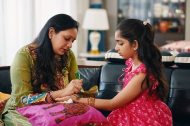 Hintli anne evde kızı için kına çiziyor.