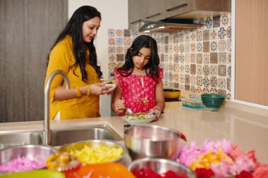 Hintli bir anne kızına mutfakta ev yemeği hazırlarken yemek yapmayı öğretiyor.