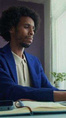 Ofis masasında dizüstü bilgisayar başında esnerken Afrika kökenli Amerikan ırkının tükenmiş solofrenisinin dikey görüntüsü.