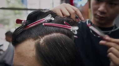 Kuaförde saç keserken, genç berberin saç fırçalarken ve saç tokalarını takarken çekilmiş.