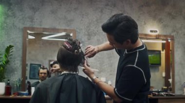 Modayı takip eden berber dükkanında yeni saç tıraşı olurken erkek müşterinin orta boy fotoğrafı.