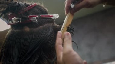 Berber dükkanında erkek müşterilerin saçlarını tararken ve keserken çekilmiş görüntüler.