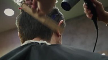 Yeni saç kesimi için kuaföre giderken erkek müşterinin fön çektirme görüntüsü düşük açılı.
