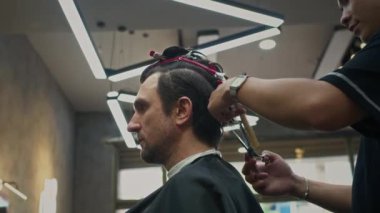 Berber dükkanında berber bekleyen orta yaşlı, beyaz bir adamın yeni bir saç modeli.