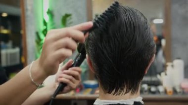 Berber dükkanında saç kesiminden sonra erkek müşterinin saçını kurutan tanınmamış berberlerin orta derecede yakın çekimleri.