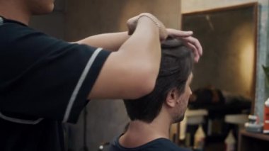 Erkek kuaförün erkek kuaför saç kesimini son moda berber dükkanında elleriyle keserken çekilmiş bir fotoğrafı.