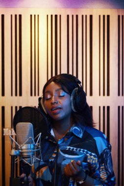 Afrikalı Amerikalı kadın kayıt stüdyosunda vokal becerilerini geliştiriyor.