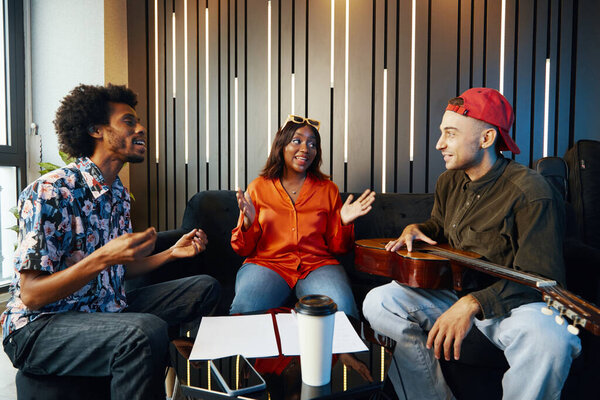 Музыкальная группа репетирует новую песню вместе, сидя в музыкальной студии