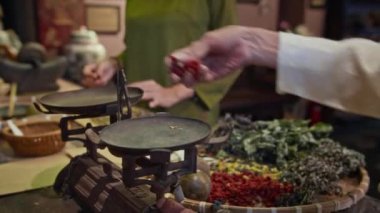 Geleneksel ilaç eczanesinde bitkisel karışım hazırlarken tanınamayan Asyalı şifacının ellerinin kesilmiş görüntüsü.