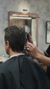 Moda salonunda stil yaparken erkek berberin saç kurutma sahnesi.