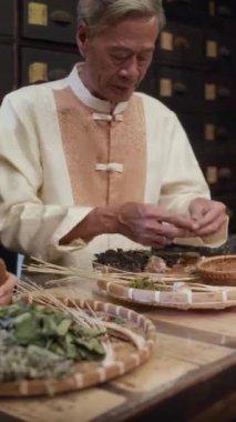 Eczacıda ilaç karışımı hazırlayan bitkisel tıp çalışanlarının dikey görüntüsü.