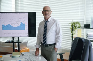 Sunum sırasında ofiste çalışırken kameraya bakan olgun sanat yönetmeninin portresi