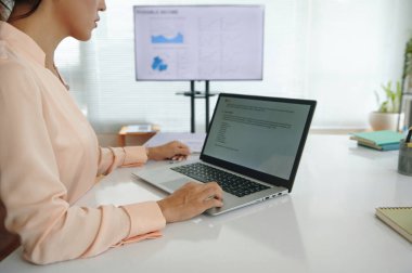 Genç iş kadını pazarlama bölümünde çalışırken dizüstü bilgisayarla proje geliştiriyor