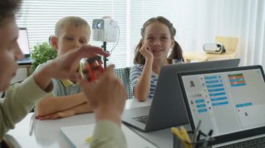 Erkek Kafkas öğretmeni okuldaki robot mühendisliği dersinde çocuklara konuyu açıklıyor.