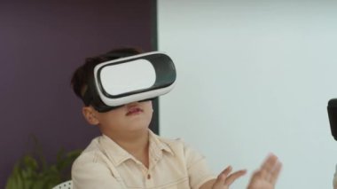 Modern okuldaki çocukların bilişim dersinde VR kulaklık kullanırken çekilmiş fotoğrafları.