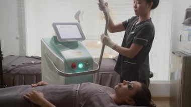 Genç bayan müşterinin, güzellik salonunda yüzüne lazer gençleştirme işlemi yapılırken elde çekilmiş bir fotoğrafı.