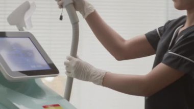 Siyah üniformalı estetisyen kadın müşterilerin alnına lazer kullanarak kuafördeki kırışıklıkları ve pigmentasyonu azaltır.