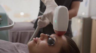 Beyaz kadın müşterinin güzellik salonunda lazer tedavisi sırasında anti-yaş tedavisi görmesi.