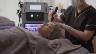 Modern klinikte rahatlamış Kafkas kadının mikro tedavi prosedürü alışının yan görüntüsü