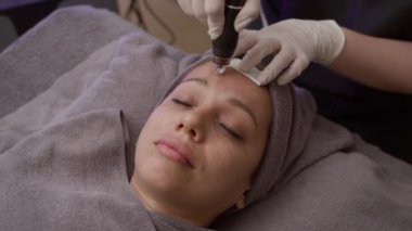 Klinikteki mikroskobik prosedür sırasında beyaz bir kadının yüzüne kırışıklık önleyici tedavi uygulanırken.