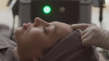 Klinikteki prosedür sırasında kadın müşterinin yüzüne kolajen enjekte eden güzellik uzmanının ellerini kapatın.