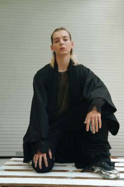 Siyah elbiseyle kameraya poz veren genç erkek mankenin portresi.