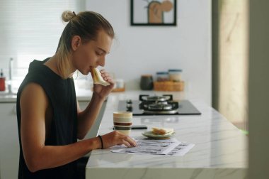 Moda mankeni mutfakta kahvaltı ederken çizimleri inceliyor.