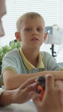 Kafkasyalı bir öğrencinin mühendislik dersinde elinde küçük bir robotla öğretmenini dinlerken dikey çekimi.