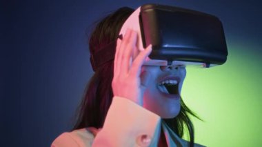 Z jenerasyonunun yakın çekim stüdyosundaki kız AR gözlüklü sanal dünyayı neon arka planda görüyor.