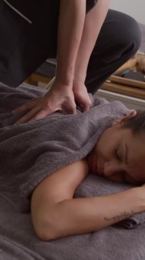 Spa salonundaki masaj sırasında kadın müşterinin sinir uçlarına osteopat baskısının dikey görüntüsü.