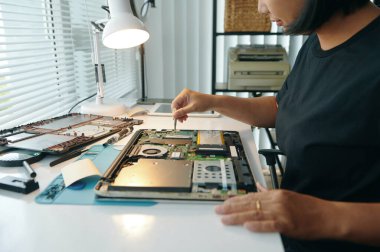 İşyerinde otururken bilgisayarı aletle kontrol eden profesyonel bir usta.