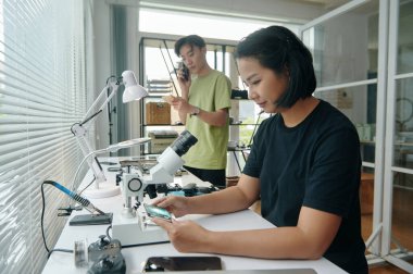 Genç bir kadın bilgisayar detaylarını incelerken o da arka planda telefonla konuşuyor.