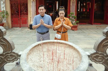 Kutsal yerin yanında dikilen ve dışarıda birlikte dua eden çift.