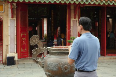 Asyalı bir adamın Budizm 'i beyan edişini, tapınağın önünde durup dua edişini.