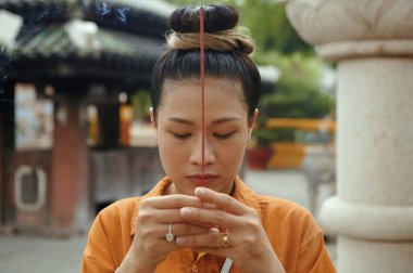 Tapınağı ziyaret ederken aroma çubuğuyla dua eden Asyalı kadın.