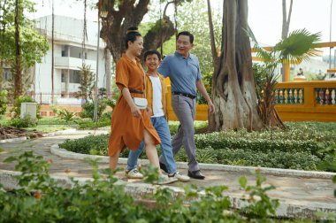 Üç kişilik Asyalı bir aile oğluyla birlikte antik kentte yürüyor.