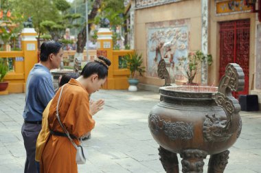 Çocuk sahibi Budist Asyalı aile tapınakta birlikte dua ediyor.
