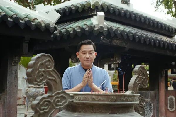 stock image Asian man praying near the cup with aroma sticks while visiting Buddhism temple