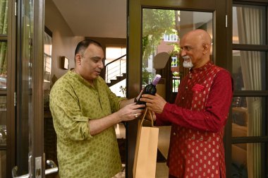 Usta adam evine gelirken arkadaşına bir şişe şarap veriyor.