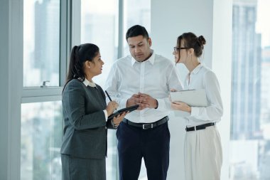 Ofis koridorunda dururken tablet bilgisayarda sunumu tartışan bir grup meslektaşım